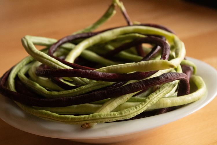 KI generiert: Ein Teller mit langen, grünen und violetten Bohnen.