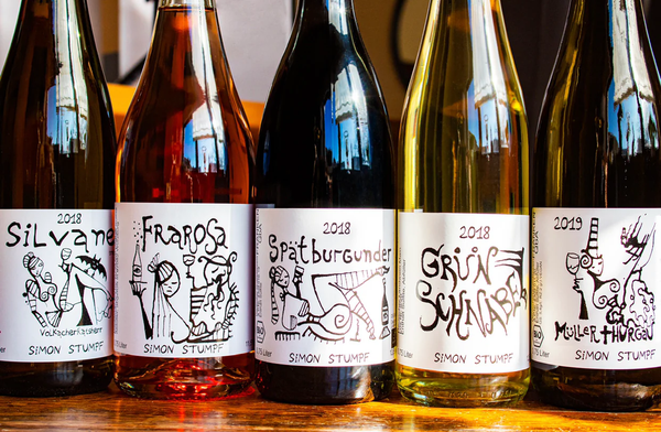 KI generiert: Fünf Weinflaschen mit künstlerisch gestalteten Etiketten und den Namen der Weine: Silvaner, Frarosa, Spätburgunder, Grüner Schnabel, Müller-Thurgau.