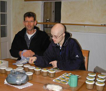 KI generiert: Zwei Personen etikettieren Gläser am Tisch. Im Vordergrund sind Marmeladengläser und Etiketten zu sehen.