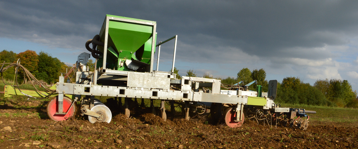 KI generiert: Eine landwirtschaftliche Maschine auf einem Feld unter bewölktem Himmel.