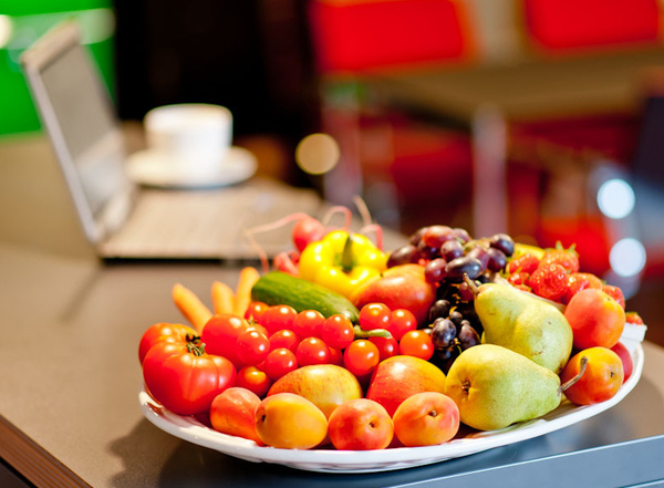 KI generiert: Ein Teller mit buntem Obst und Gemüse steht vor einem Laptop auf einem Tisch.