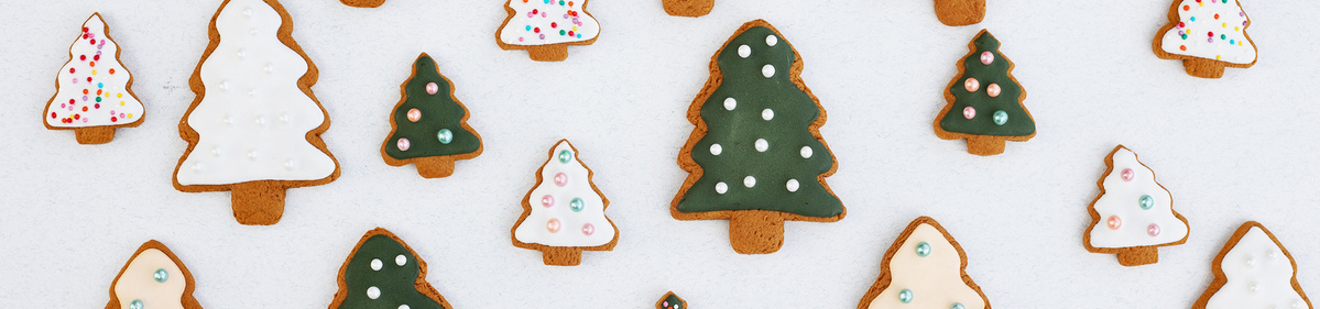 KI generiert: Weihnachtsbaum-Plätzchen mit Zuckerglasur und Streuseln auf weißem Hintergrund.