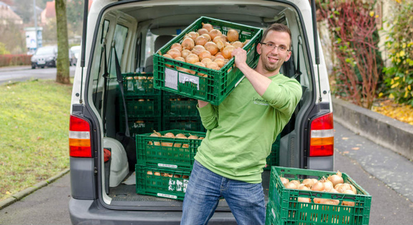 KI generiert: Ein Mann lädt Kisten mit Zwiebeln in einen Lieferwagen.