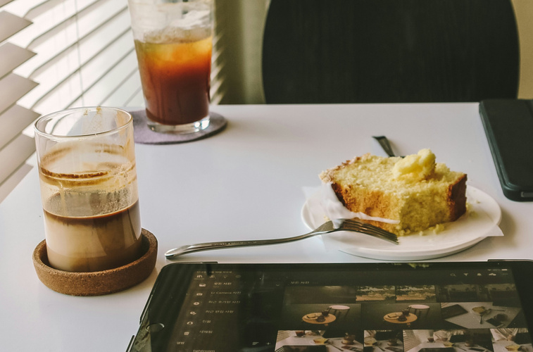 KI generiert: Ein Tisch mit Latte, Kuchenstück, Eiskaffee und Tablet.