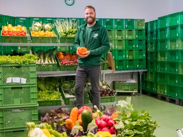 Freundlicher Packer in unserer Packhalle mit Gemüse und Obst