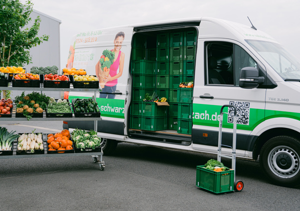 KI generiert: Ein Lieferwagen mit Gemüse und Obst in grünen Kisten. Text: Telefonnummer und Webadresse auf dem Fahrzeug.