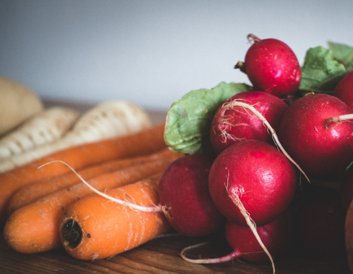KI generiert: Frisches Gemüse: Radieschen und Karotten auf einem Holztisch.