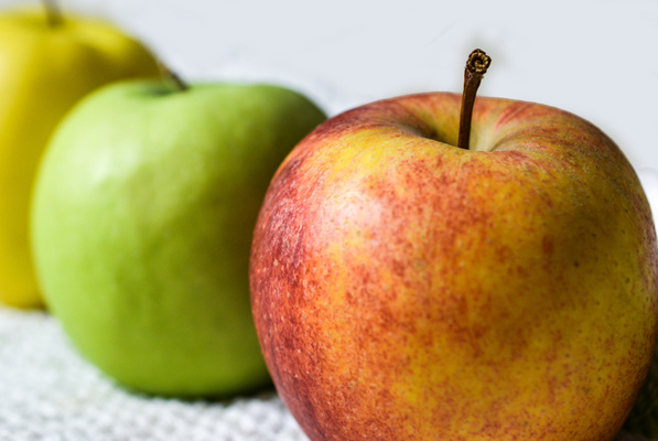 KI generiert: Drei Äpfel in verschiedenen Farben nebeneinander.