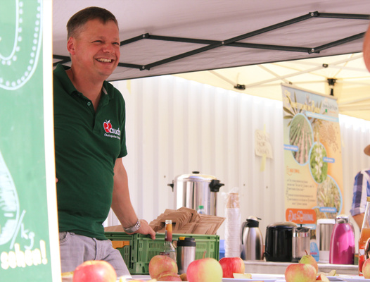 KI generiert: Ein Mann verkauft Äpfel an einem Marktstand unter einem Zelt.