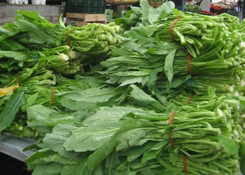 KI generiert: Ein Tisch voller Bündel frischer, grüner Blattgemüse.